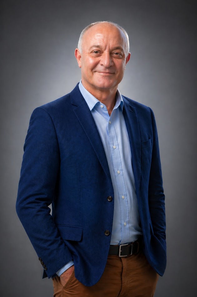 Retrato de Marcelo Barone, de blazer azul, em fundo cinza